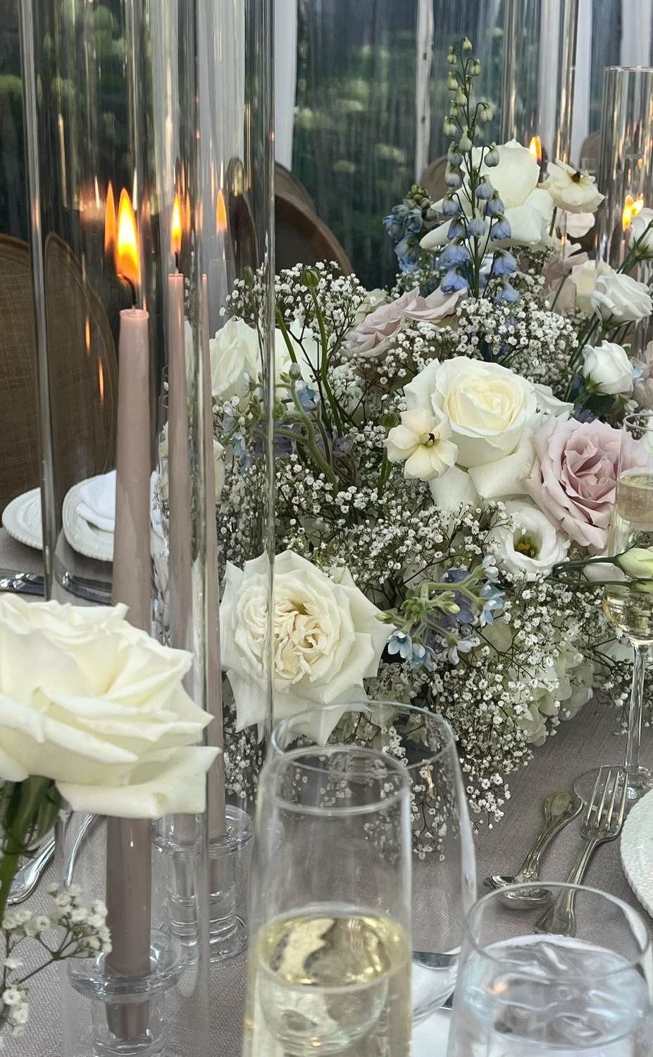 A macro shot of white and blush roses and taper candles