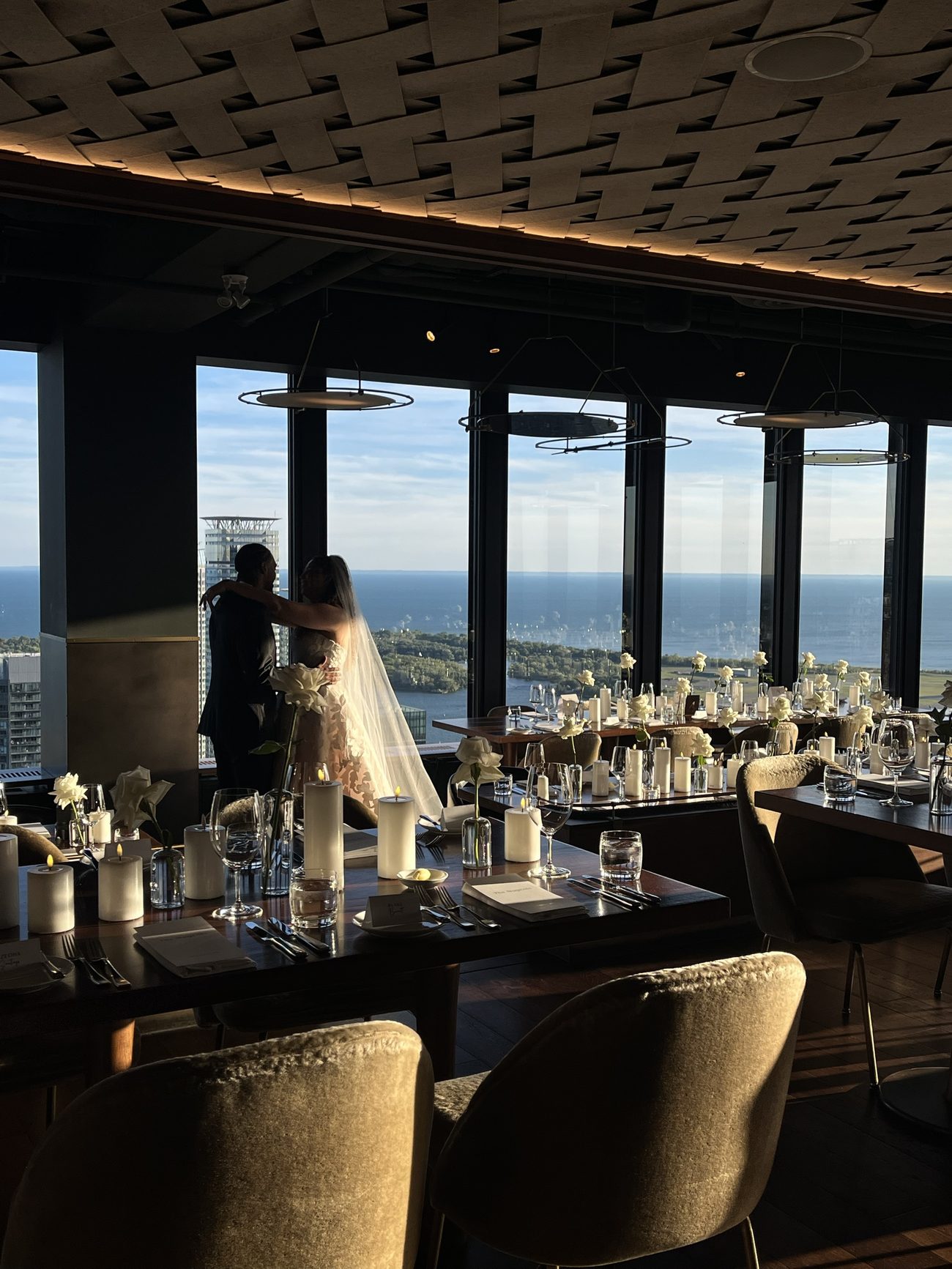 A couple sharing a quiet moment at a rooftop reception overlooking the Toronto skyline at sunset
